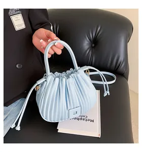 Detail van lichtblauwe geplooide handtas met trekkoord en decoratieve vierkante gesp