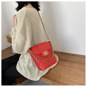 Close-up of red quilted bucket bag with golden chain strap and double ring clasp
