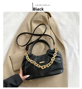 Macro detail of black pleated PU bag with decorative chunky gold chain and metal studs
