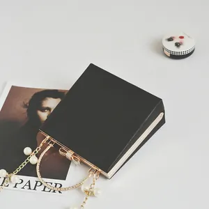 Elegant black leather square handbag with golden bow clasp and pearl chain handle
