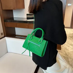 Vibrant green crocodile pattern PU leather crossbody bag with tassel details shown on model