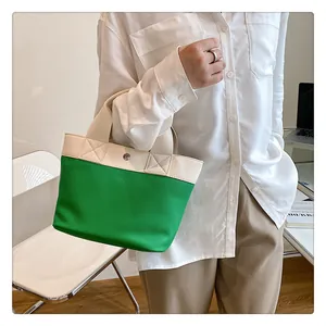 Dettaglio della borsa tote in PU bicolore verde e crema con chiusura a scatto metallica