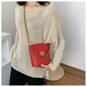 Model wearing red quilted bucket bag with gold interlocking buckle and chunky chain strap