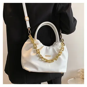 Detail view of white ruched cloud bag featuring gold chain and adjustable shoulder strap