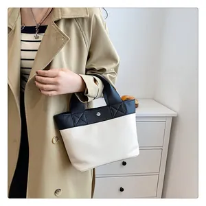 Dettaglio cuciture a contrasto su borsa a mano bicolore in ecopelle crema e nera