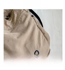 Close-up of khaki nylon backpack fabric featuring dual-ring embroidery and drawstring detail