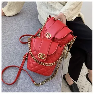 Detail of red quilted leather bucket bags with gold interlocking clasp and chain strap