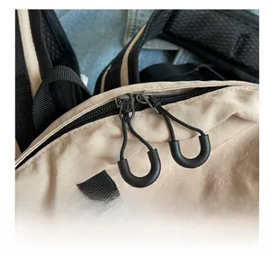 Detail of smooth two-way black zippers and U-shaped pullers on beige nylon backpack