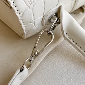 Detailansicht des hochwertigen silbernen Metallhakens an weißer Kroko-Lederhandtasche