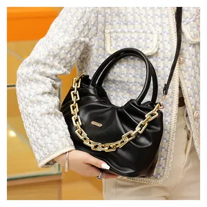 Detail of black pleated PU crossbody bag featuring gold chain and round handles