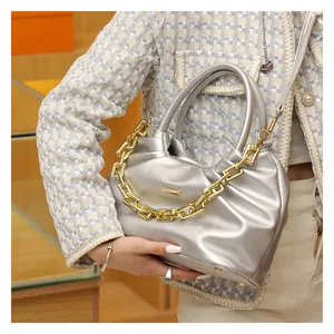 Detail of silver PU leather crossbody bag featuring a bold decorative gold chain and logo
