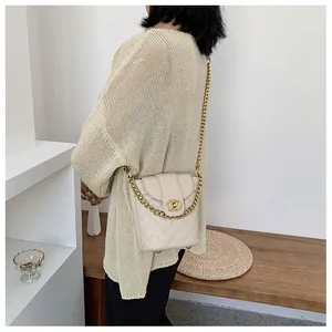 Close-up of quilted cream bucket bag with chain strap worn by model in a chic interior