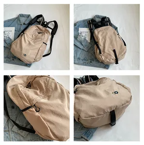 Detail of minimalist beige nylon backpack featuring a round embroidered logo and side pocket