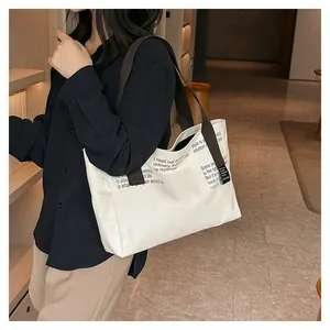 Détail d'un grand sac cabas en toile blanche avec imprimé texte et sangle marron