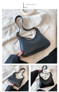 Detail view of black PU leather crescent underarm bag with gold buckles and adjustable strap