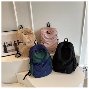 Detail showing simple nylon backpacks in khaki, pink, navy, and black with round logo