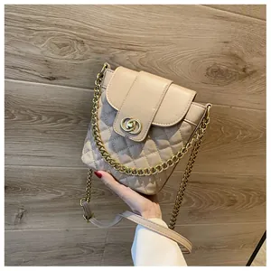 Detail of quilted leather texture and interlocking gold buckle on beige bucket bag