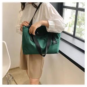 Détail d'un grand sac cabas en toile vert foncé avec de larges bandoulières noires