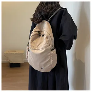 Detail of beige minimalist backpack showing micro-texture fabric and blue circular logo