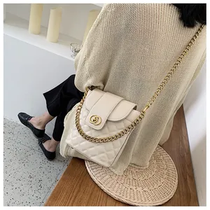 Detail of cream quilted crossbody bucket bag with gold chain and circular metal lock