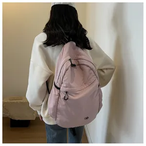 Rear view of minimalist pink nylon backpack worn by model in a bright indoor setting