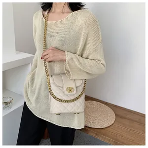 Detail of quilted beige bucket bag with gold chain strap worn by a model in a minimal room