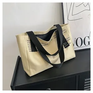 Sac fourre-tout minimaliste en toile beige avec bandoulière noire et texte déco