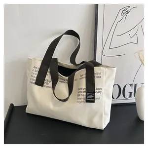 Détail du grand sac cabas en toile montrant les poignées et la typographie noire