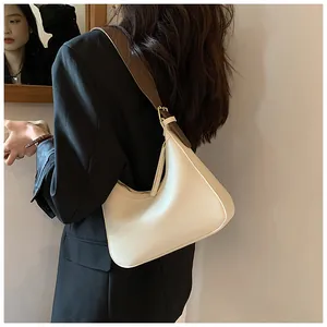 Detail of minimalist cream PU leather hobo bag with contrast brown strap and gold buckle