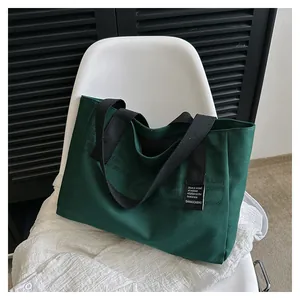Détail du sac fourre-tout en toile vert foncé avec typographie et large poignée noire