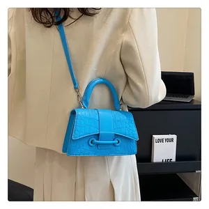 Detailansicht einer hellblauen Handtasche mit Krokodilprägung und Schultergurt in der Stadt