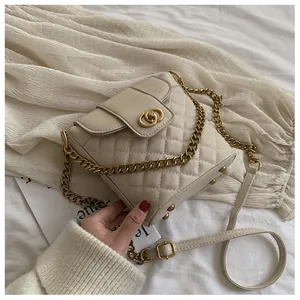 Close-up of cream quilted crossbody bag with gold double-ring clasp and chain strap