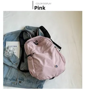 Detailed top view of light pink casual nylon backpack with black mesh straps and side decor