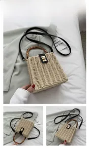 Detail of woven straw box bag with bamboo handle and black leather flap with gold lock