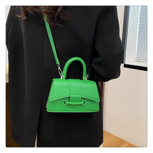 Modische grüne Sanduhr-Handtasche mit Krokodilmuster über einem schwarzen Blazer