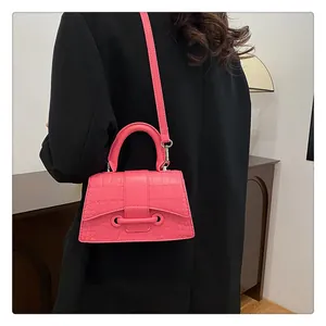 Detail der pinkfarbenen Handtasche mit Krokodilprägung auf einem schwarzen Blazer