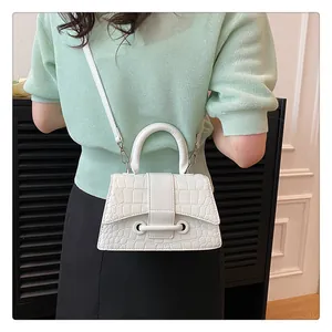 Moderne weiße Handtasche aus Kunstleder mit Krokoprägung, getragen von einem Model