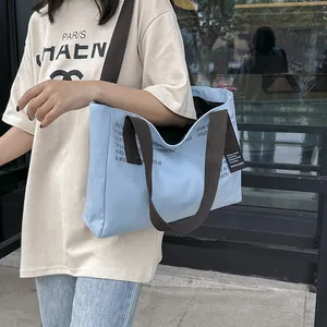 Sac cabas en toile bleu clair avec large bandoulière marron et texte de style urbain