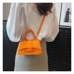 Detail der lebhaften orangen Handtasche mit Steinmuster, festem Griff und Umhängeriemen