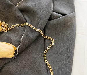 Detailed close-up of shiny gold metal chain strap on vintage crane print handbag