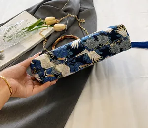 Detail view of the embroidered crane pattern bag with bamboo handle and blue tassel