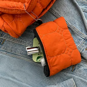 Detail van de oranje gewatteerde mini-tas met metalen kralenketting op denim ondergrond