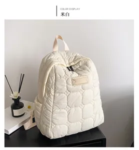 Detail of cream white quilted backpack on a desk with decor in minimalist setting