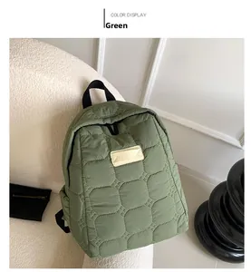 Close-up of green quilted backpack featuring hexagonal patterns and beige logo patch