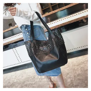 Dettaglio della borsa tote in pelle PU nera con borchie argentate indossata dal modello