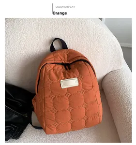 Detailed shot of orange quilted backpack with grid stitching on a soft cream sofa