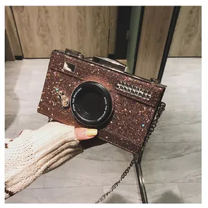Detail of glitter camera-shaped bag featuring metallic chain strap and textured finish