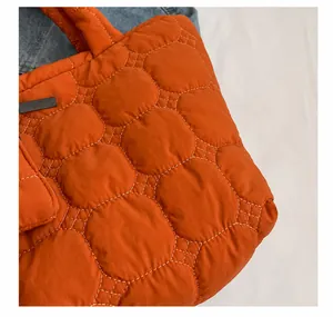 Macro-opname van oranje gewatteerde tas met witte geometrische stikseldetails