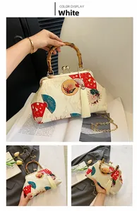 Detail of bamboo handle and red fan print on white vintage style handbag with tassel