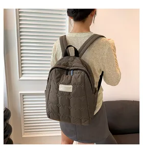 Close-up of brown quilted backpack showing stitch detail and adjustable black straps